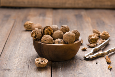 Walnuts in wooden bowl on table with Nutcracker.の写真素材