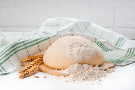 Ball of raw dough isolated on white wooden table with ears wheat copy space.の写真素材