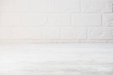 White wooden table on white brick wall. Copy space.