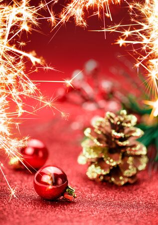 Christmas holiday concept. Red Christmas balls with star and Christmas branch tree on red background. Bokeh. Bengal fire.の写真素材