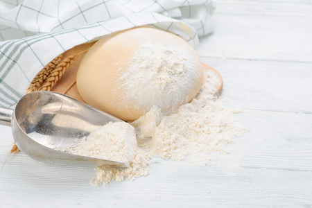 Ball of raw dough isolated on white wooden table with ears wheat and napkin. Copy space. Top view.の写真素材