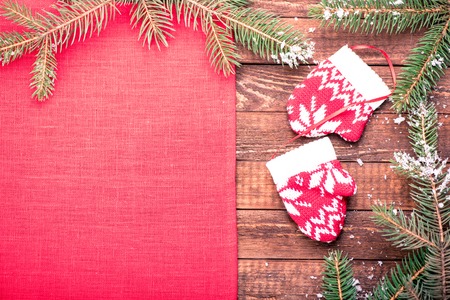 Christmas toy. Mittens. Christmas holiday celebration concept. Red napkin on wooden table with Christmas tree brunch. Top view.の写真素材