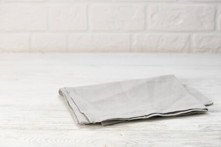 Gray napkin isolated on white wooden table. Copy space. White brick wall background. Front view.の写真素材