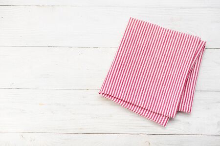 Red rustic napkin isolated on white wooden table. Copy space. Top view.の写真素材