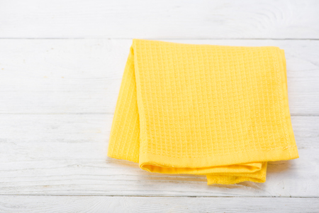 Yellow napkin isolated on white wooden table. Copy space. Top view.の写真素材