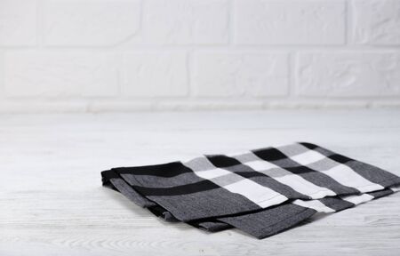 Black and white napkin. The checkered tablecloth on wooden table. Brick wall background. Copy space. Front view.の写真素材