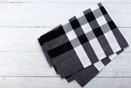 Black and white napkin. The checkered tablecloth on wooden table. Copy space. Top view.の写真素材