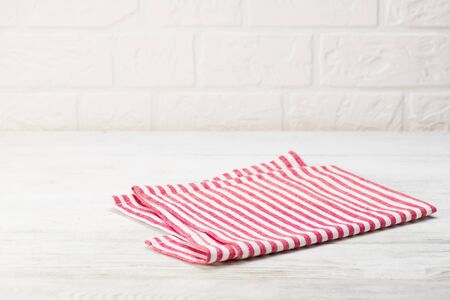 Red napkin isolated on white wooden table. Copy space. White brick wall background. Front view.の写真素材