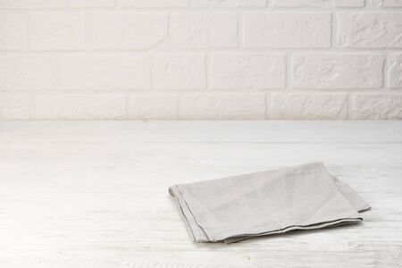 Gray napkin isolated on white wooden table. Copy space. White brick wall background. Front view.の写真素材