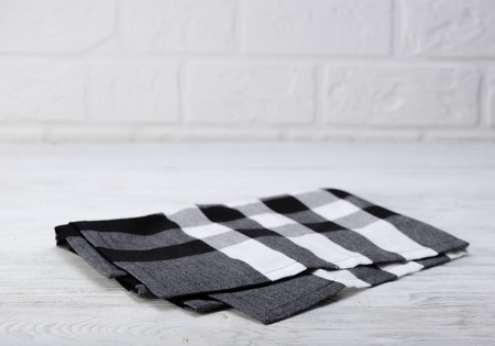 Black and white napkin. The checkered tablecloth on wooden table. Brick wall background. Copy space. Front view.の写真素材
