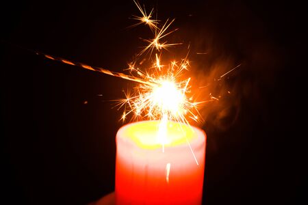 Christmas bengal fire and red candle isolated on black backgroundの写真素材