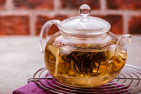 Glass teapot with tea on cooling rack. Front view.の写真素材