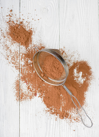 Cocoa powder in a sieve isolated on white wooden background. Top view.の写真素材