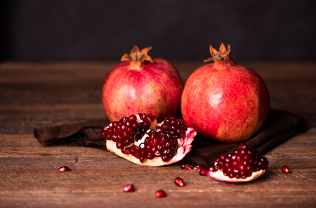 Pomegranate fruits with grains on wooden table. Dark moody. Life style.の写真素材