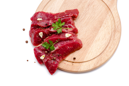 Pieces of meat with garlic and parsley on wooden board isolated. Raw beef. Meat. Top view.の写真素材