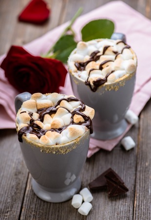 Smores drink. Two mugs of hot chocolate with marshmallows on a wooden table. Cocoa. Rose petals. Valentine.の写真素材