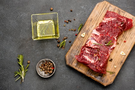 raw meat with olive oil spices and rosemary on wooden board fresh beef ready to roasting top viewの写真素材