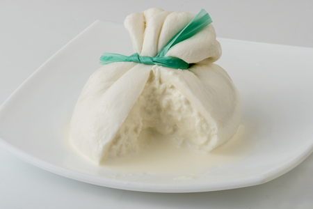 Burrata cheese isolated on white plate. Sliced fresh italian cheese made from mozzarella and cream.の写真素材