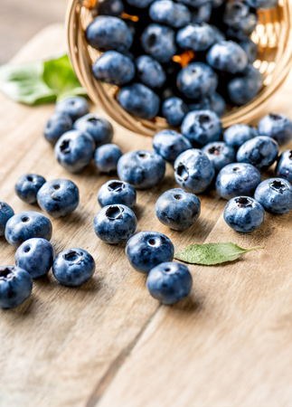 Freshly blueberries on wooden rustic wooden table. Juicy and fresh blueberries with green leaves. Bilberry on wooden background. Blueberry antioxidant. Concept for healthy eating and nutrition.の写真素材
