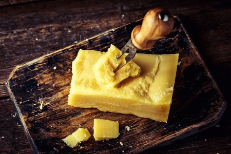 Parmesan cheese on rustic wooden board. Pieces of cheese parmesan on wooden table with cheese knife. Top view.の写真素材