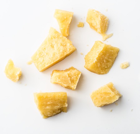 Parmesan cheese pieces on white background. Italian cheese slices. Top view.の写真素材