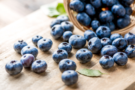 Freshly blueberries on wooden rustic wooden table. Juicy and fresh blueberries with green leaves. Bilberry on wooden background. Blueberry antioxidant. Concept for healthy eating and nutrition.の写真素材