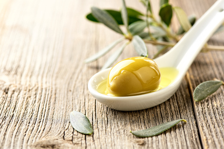 Olives, olive oil and olive branch on wooden light table with copy space for design.の写真素材