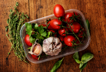 Ingredients for the salad and thyme on wooden background. Tomatoes cherry, garlic, basil, parsley. Top view.の写真素材
