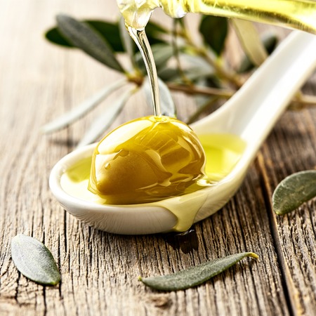 Olives, olive oil and olive branch on wooden light table with copy space for design.の写真素材