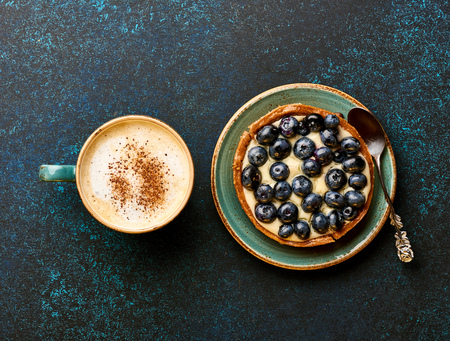 Blueberry tart with cup of coffee on blue stone background.の写真素材