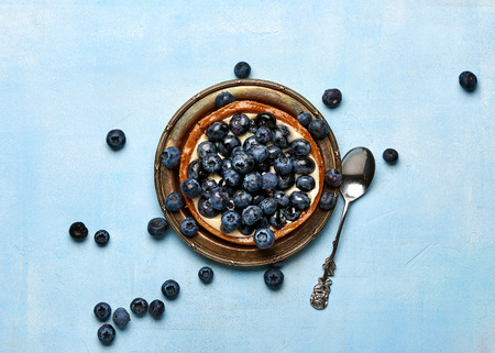 Blueberry tart, pie, tartlet with custard on blue stone background.の写真素材