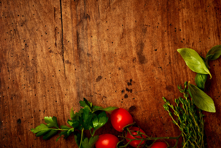 Ingredients for the salad on wooden background. Tomatoes cherry, garlic, basil, parsley. Top view.の写真素材