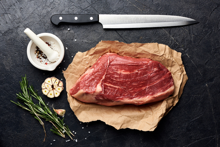 Raw fresh marbled meat Black Angus steak and meat knife. Meat on black background with rosemary, spices, olive oil and garlic. Top view.の写真素材