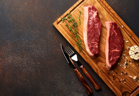 Raw fresh meat Picanha steak, traditional Brazilian cut with rosemary, garlic, knife and black pepper on wooden board. Sliced meat steaks. Copy space. Top view.の写真素材