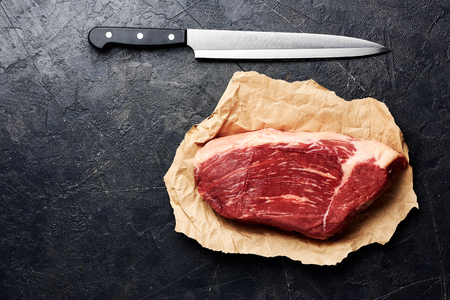 Raw fresh marbled meat Black Angus steak and meat knife. Meat on black background with copy space. Top view.の写真素材