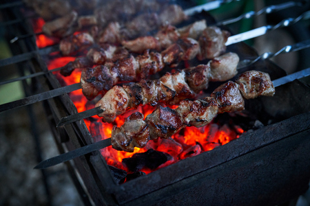 Shashlik preparing on a barbecue grill over charcoal. Pieces of meat on skewers. Shish kebab prepare on fire.の写真素材