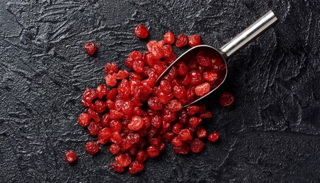 Dried red cherries on a black background with scoopの写真素材