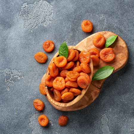 Dried apricots with green leaves on gray background. Top view.の写真素材