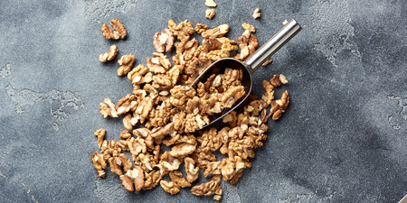 Heap of walnut kernels with scoop on gray background. Top view.