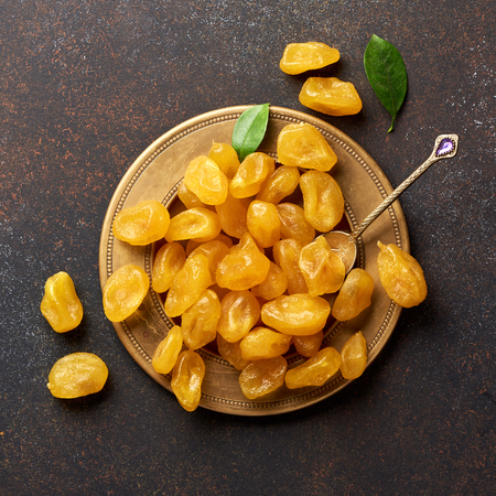 Dried yellow kumquat with green leaves on brown background. Top view.の写真素材
