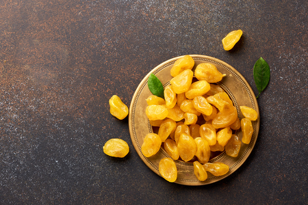 Dried yellow kumquat with green leaves on brown background. Top view.の写真素材