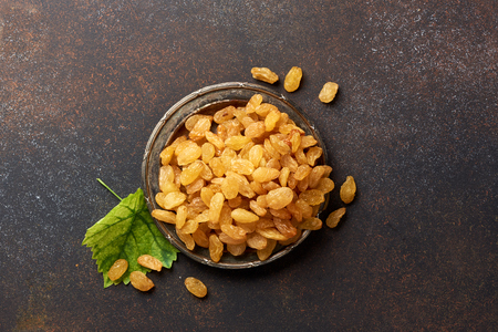 Heap of yellow raisins. Top view of dried grapes with green leaf.の写真素材