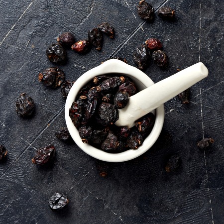 Dried rosehip in mortar over black background.の写真素材