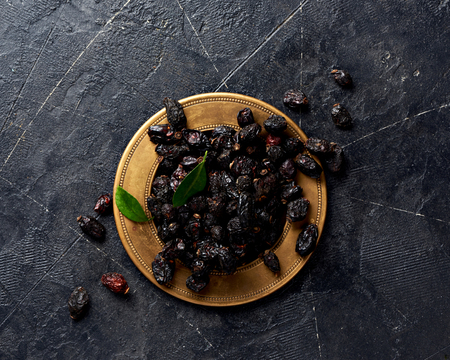 Dried rosehip on plate over black background.の写真素材