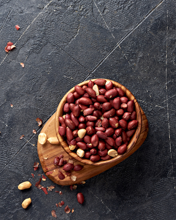 Bowl of fried peanut on black background. Top view.の写真素材
