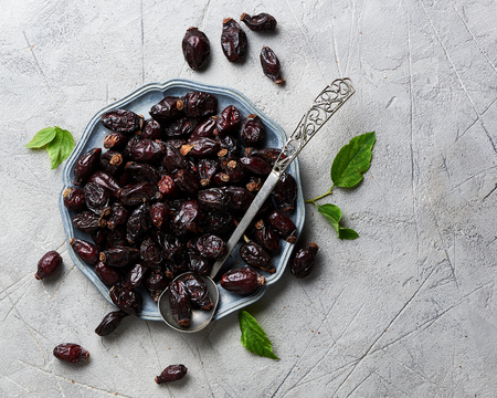 Dried rosehip with green leaves on plate over black background.の写真素材