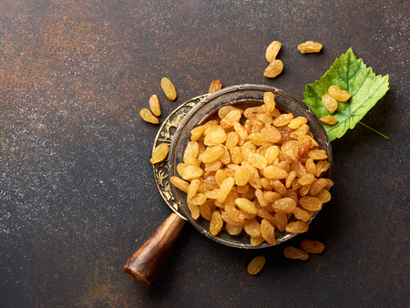 Heap of yellow raisins. Top view of dried grapes with green leaf.の写真素材