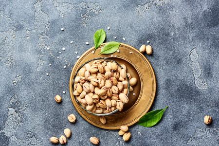 Salted Pistachios with green leaves. Top view of snacks.の写真素材