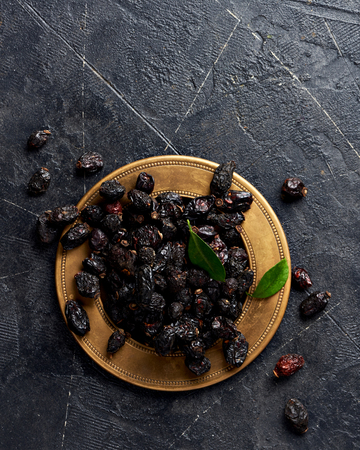 Dried rosehip on plate over black background.の写真素材