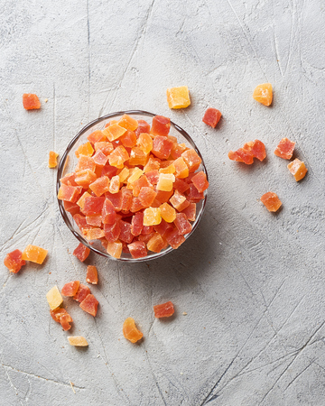 Cubes of dried apricot, mango and papaya in bowl. Candied fruits over gray background with copy space. Top view.の写真素材